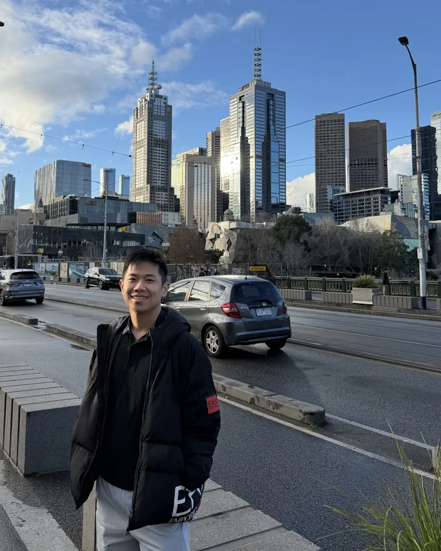 Winson smiling with the Melbourne skyline behind him